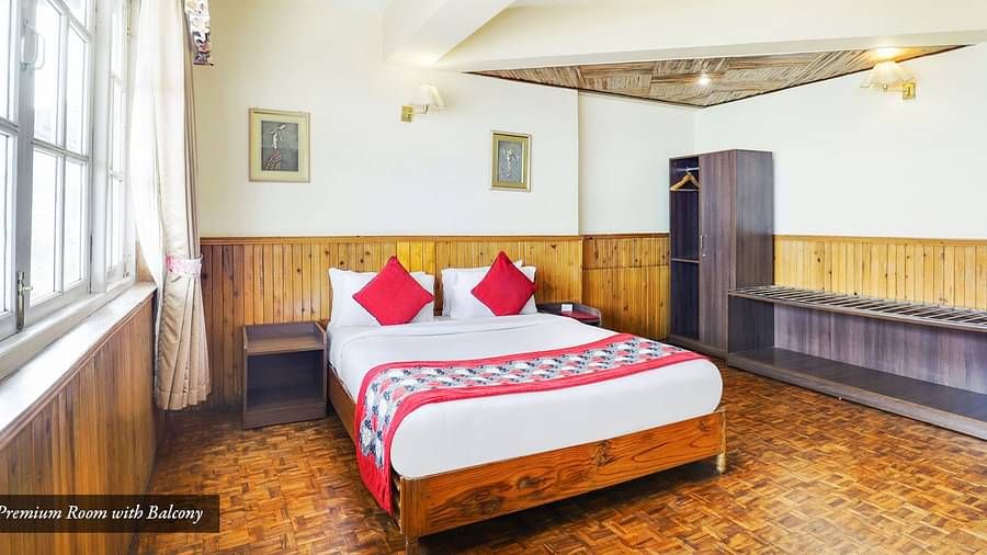 A bed in a room that has a huge glass window A front view of the beds placed in a room that has a glass window | Summit Newa Regency & Spa, Pelling