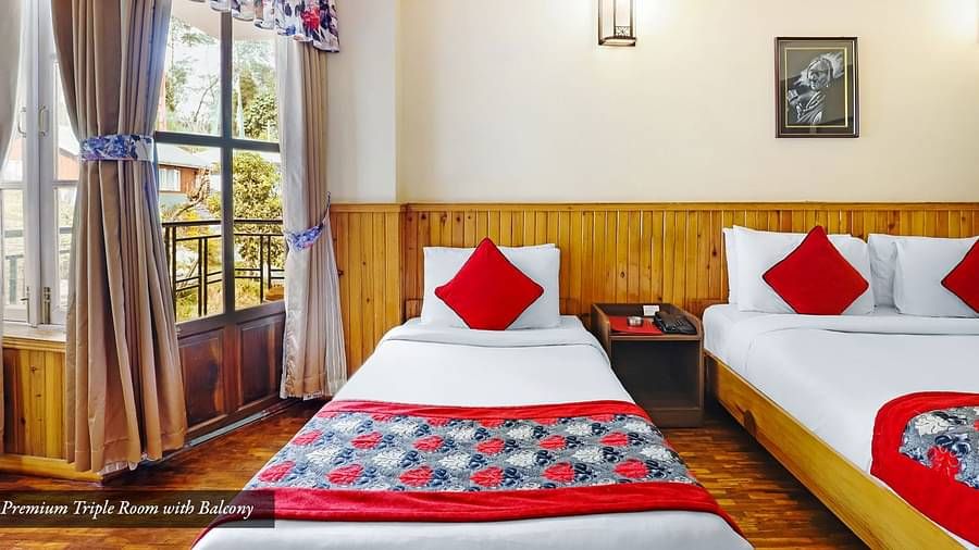 A front view of the beds placed in a room that has a glass window | Summit Newa Regency & Spa, Pelling