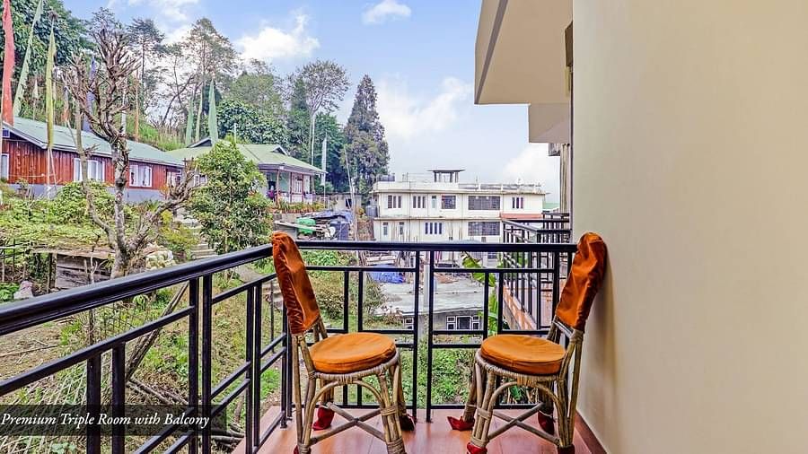 A side view of two chairs placed in a balcony that has a view of greenery | Summit Newa Regency & Spa, Pelling