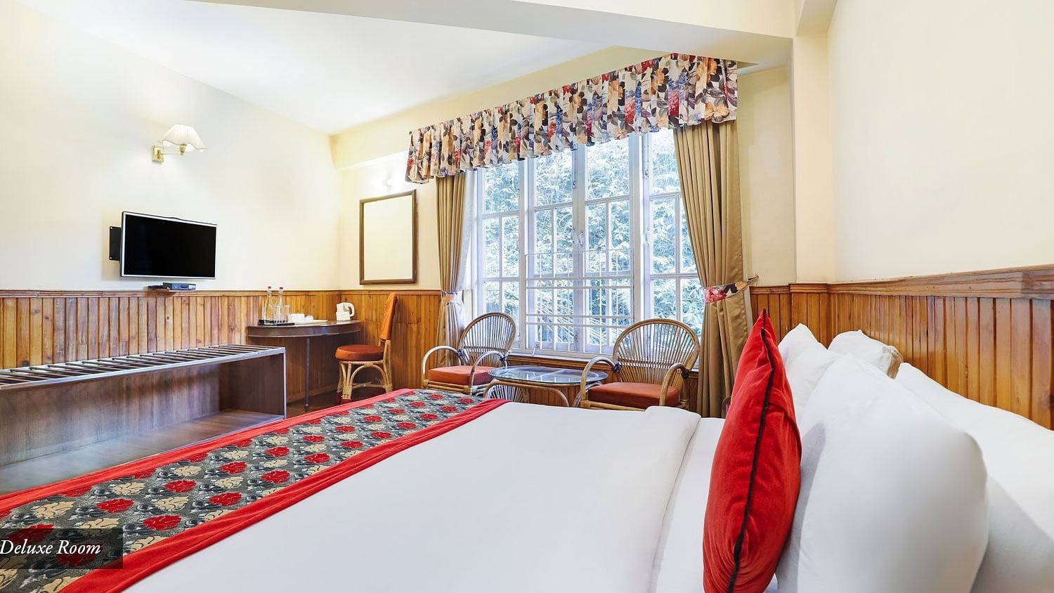A side view of a bed in a room that has a huge glass window and a TV on a wall | Summit Newa Regency & Spa, Pelling