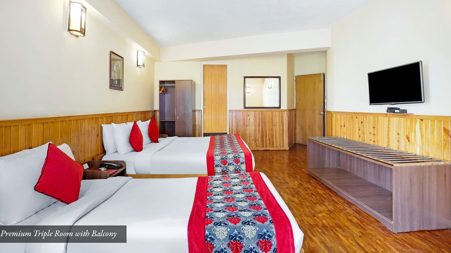 A side view of beds placed in a room that has a TV on the wall | Summit Newa Regency & Spa, Pelling
