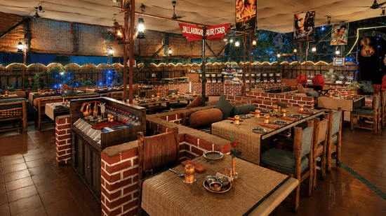 Open air restaurant at Pride Premier Pune with wooden tables, brick accents and evening lighting.