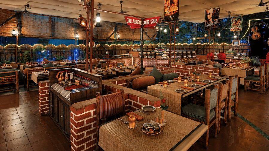 Open air restaurant at Pride Premier Pune with wooden tables, brick accents and evening lighting.
