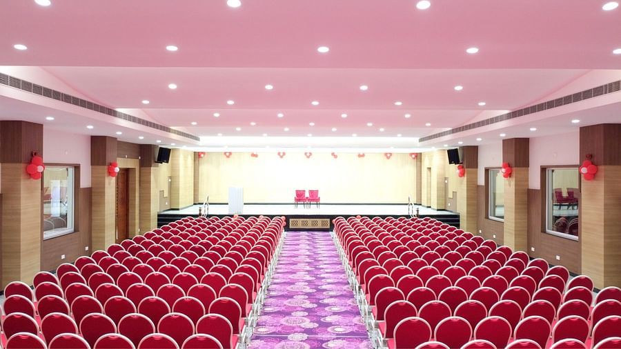 An event hall with multiple chairs facing the stage at Grand Ashok, Thanjavur.