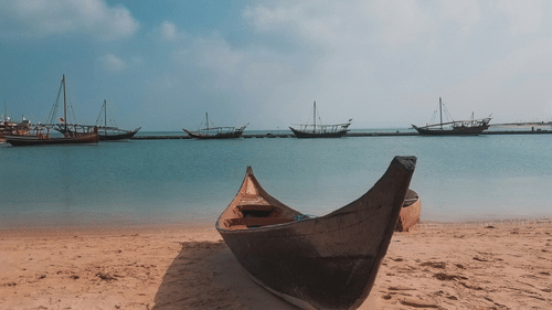 A fishing boat parked on Katara Beach with other boats in the sea.