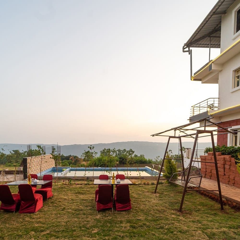 Outdoor lawn area next to a swimming pool featuring seating arrangements and a swing.