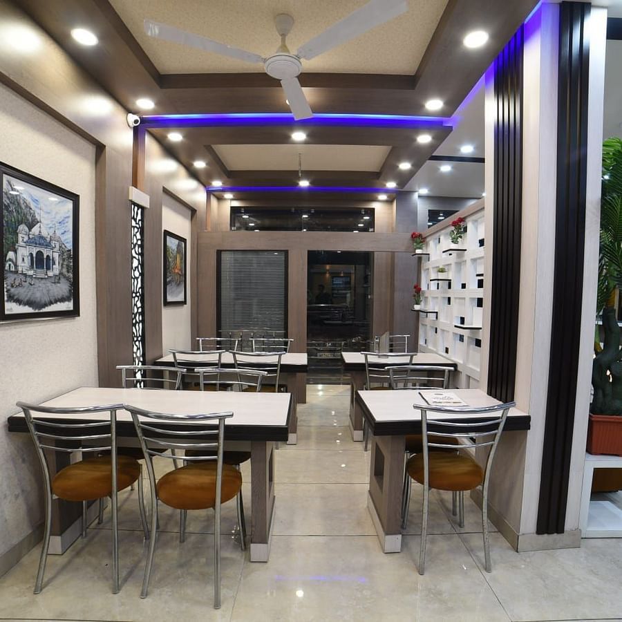 Restaurant with white tables and chairs at Hotel Panchvati Inn