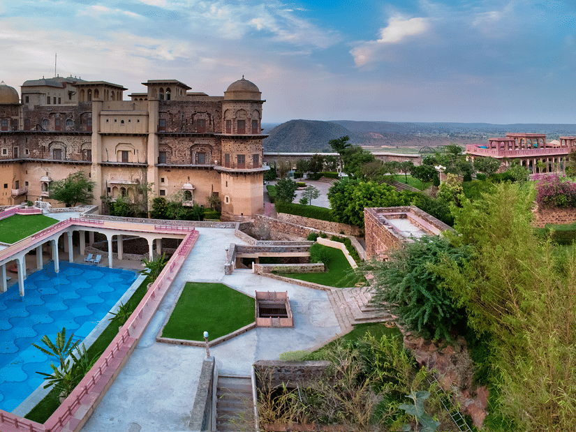 Facade view of  Tijara Fort-Palace - 19th Century, Alwar with a swimming pool in the foreground.