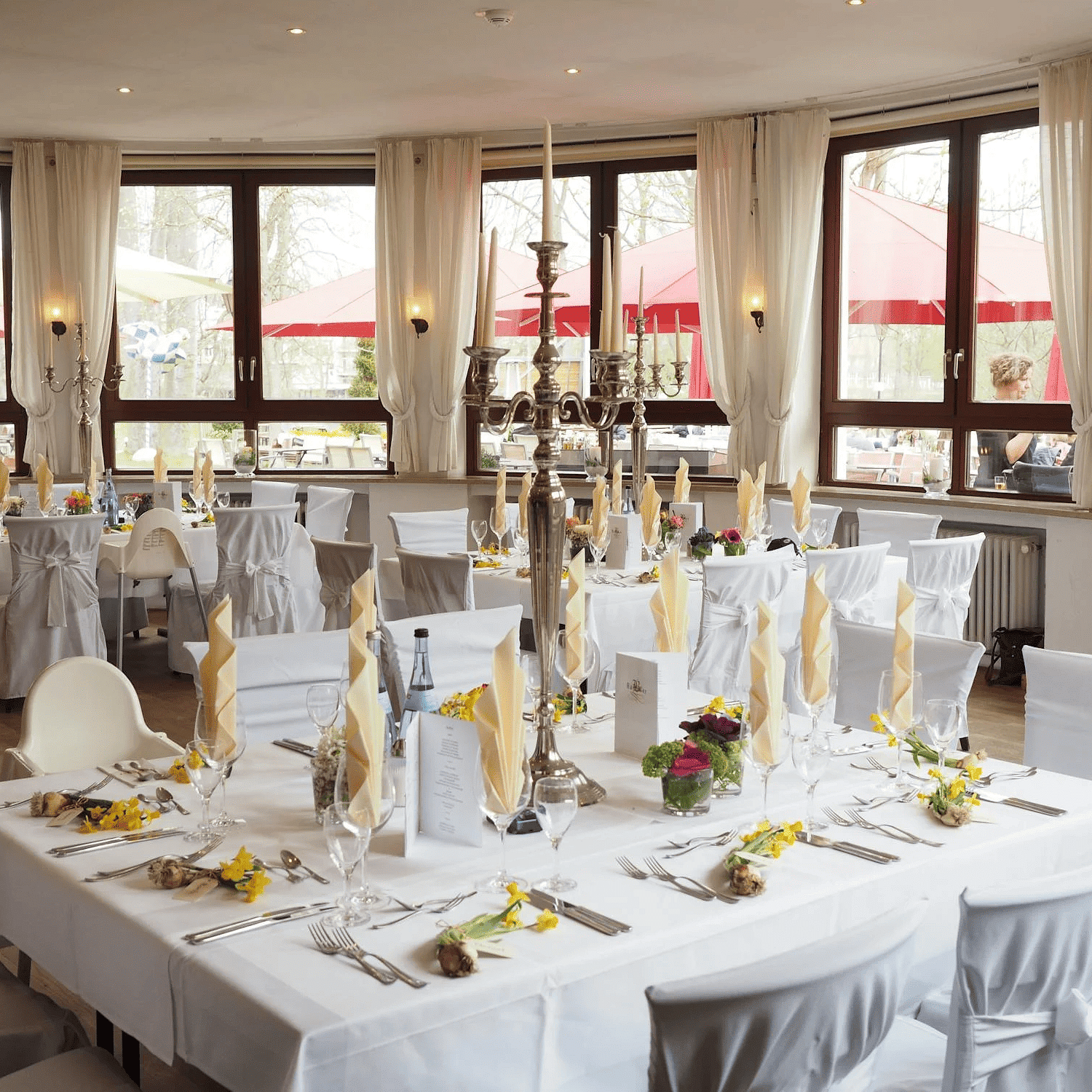 Image of a banquet hall with cutleries and napkins placed in the glasses. 