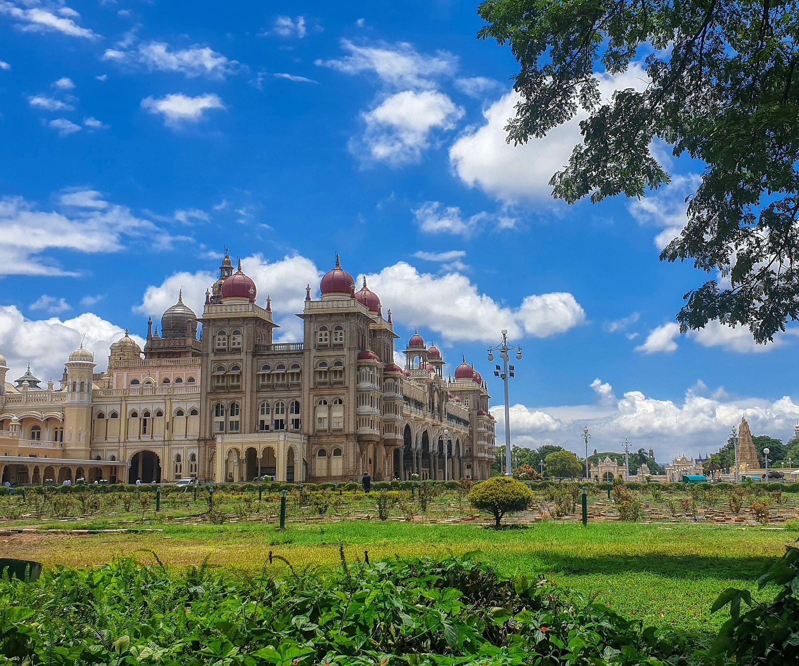 A far out view of the mysore palace with a manicured garden in the foreground