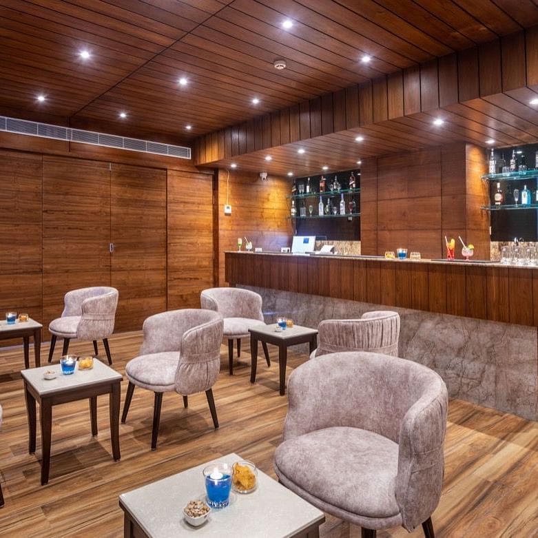 Cozy bar or lounge area with wooden paneling, soft lighting, and cushioned chairs around small tables.