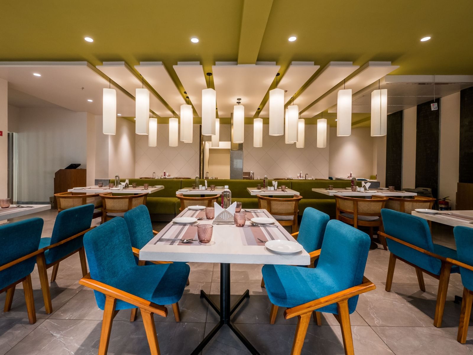 A neatly set dining table with elegant blue chairs and modern decor in a well lit restaurant environment at Shilton Dee Cee.