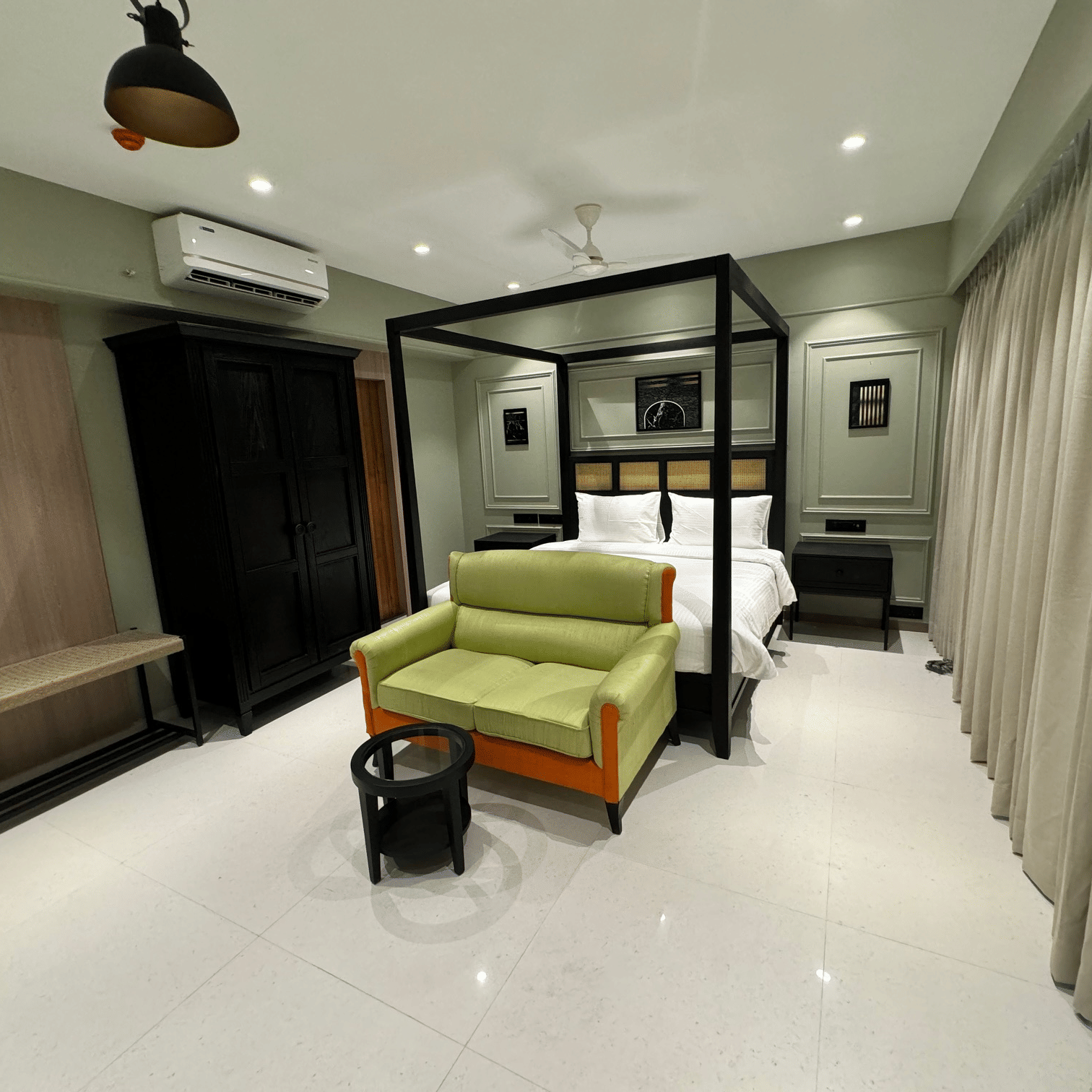 side view of a king bed with a sofa in front of it inside luxury room - Hotel Mumbai House, Valnai, Malad