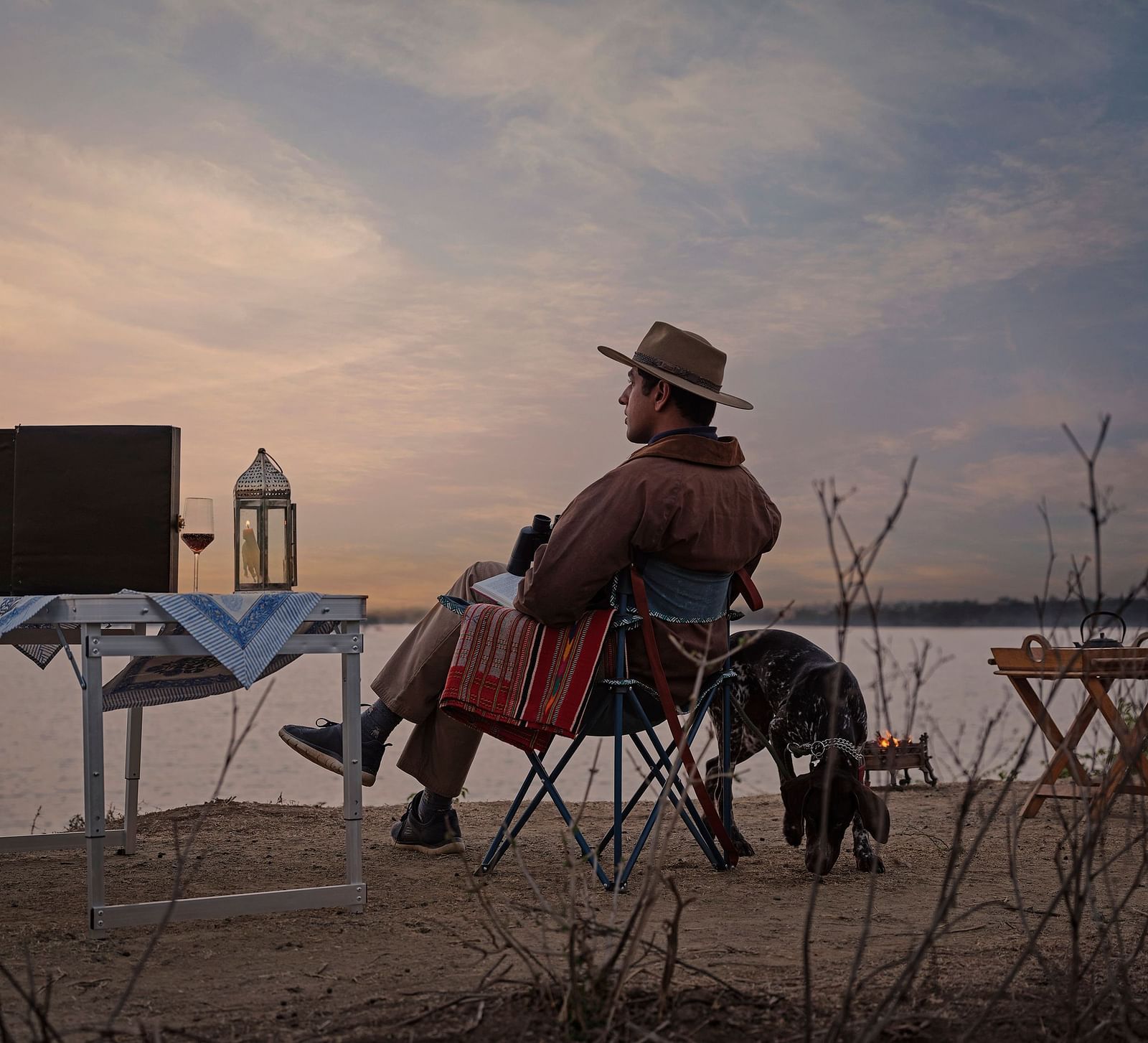image of a man relaxing and enjoying the mesmerising sunset with a serene lake in front of him at dev shree deogarh