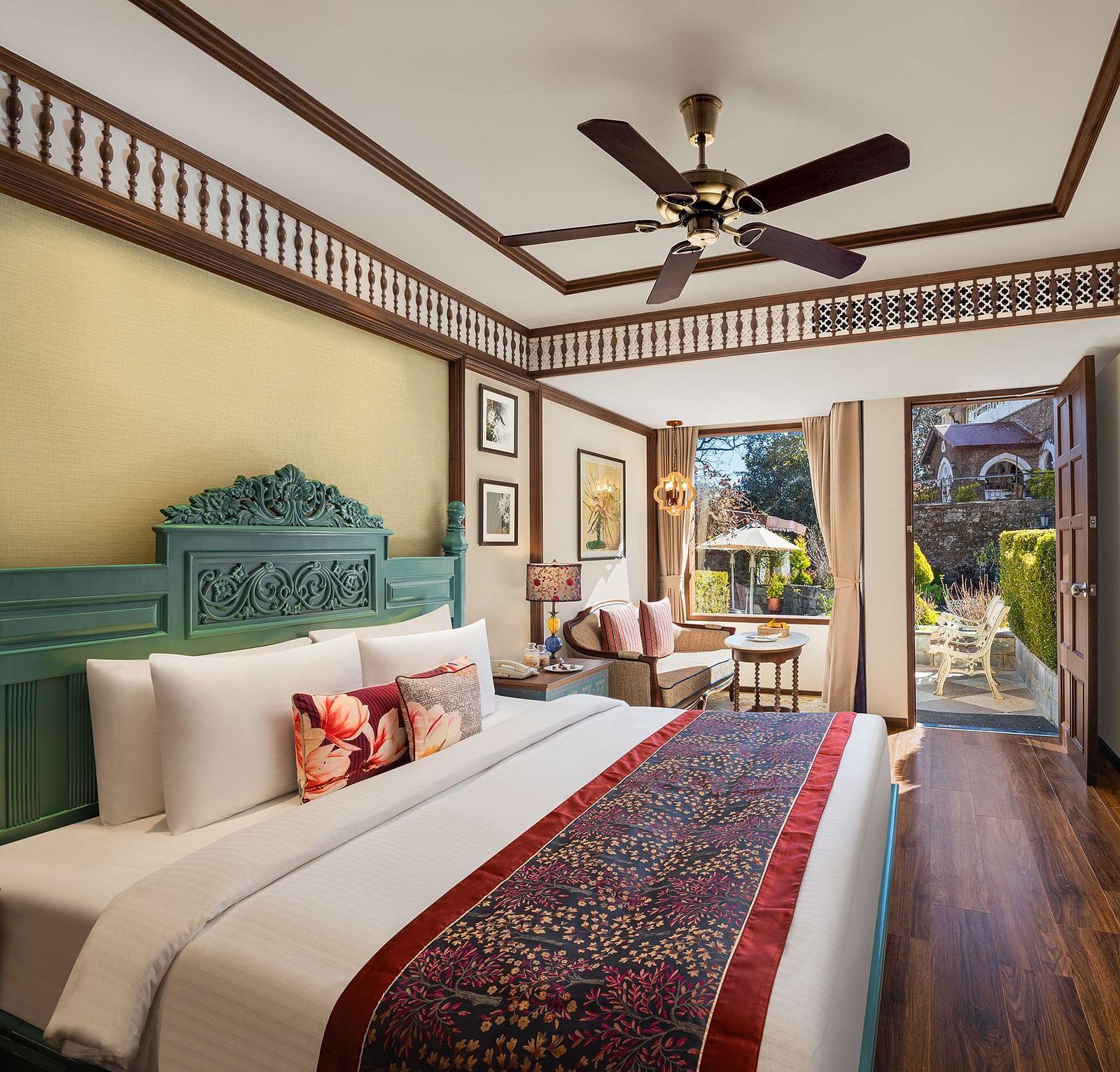 An image featuring premium Garden Room at naini retreat, nainital, A cozy and inviting hotel room with a king-size bed, The room features a small sitting area with a sofa and a side table, as well as a large window overlooking a garden.