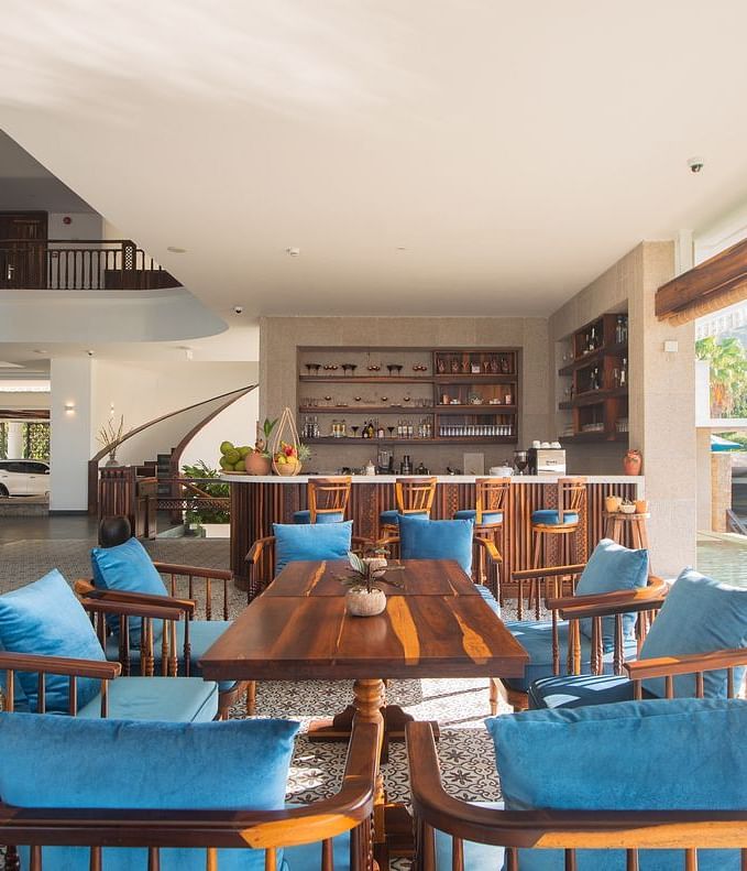 A restaurant with wooden furniture for sitting and a serene view of the pool through a glass door - Alibu Resort Nha Tarng