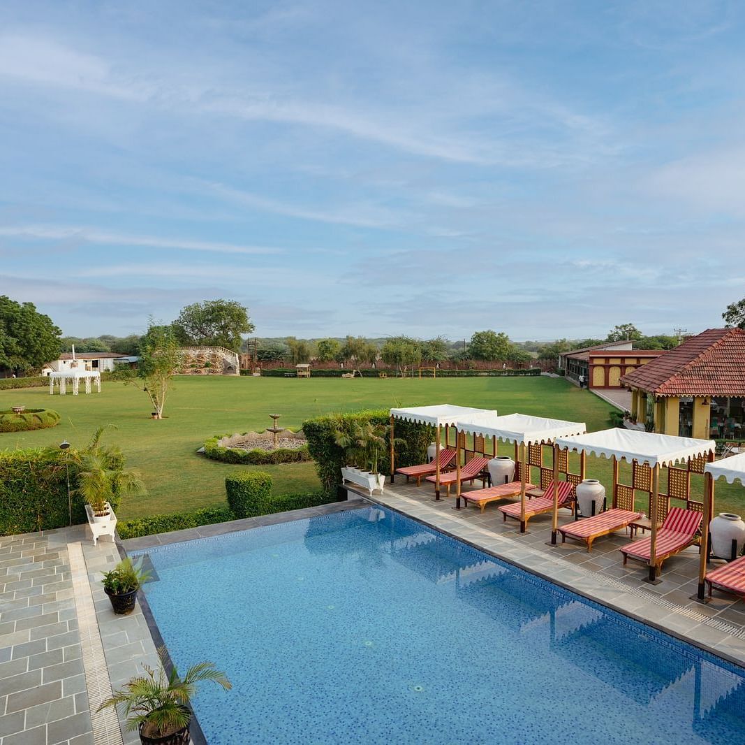 Aerial view of a swimming pool with lounge chairs on the side at Surpura Bagh.