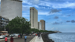 An overview of Marine Drive in Mumbai, the Best Tourist Spot in Mumbai, with cars, buildings, the sea and people in view