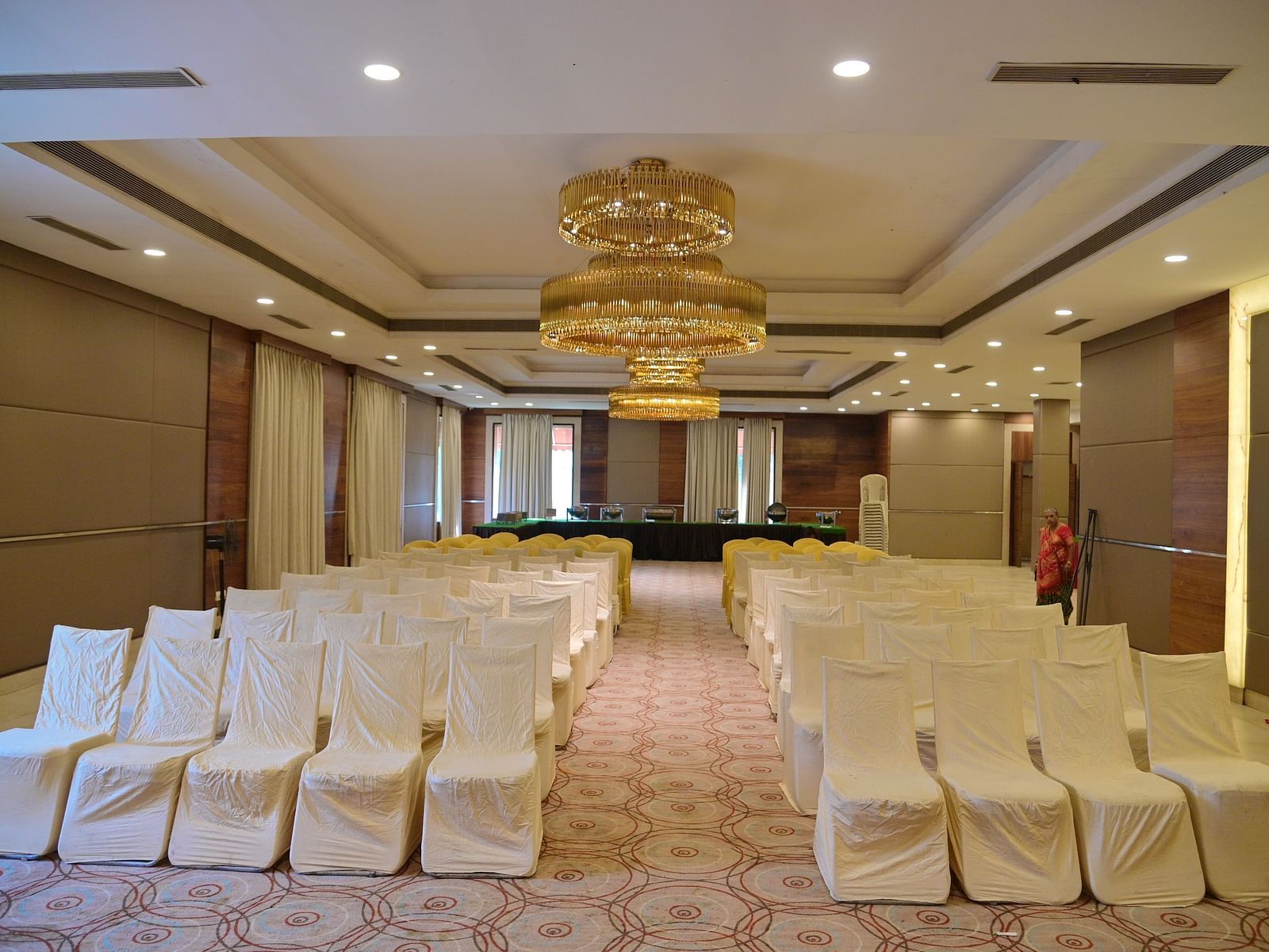 Banquet hall with rows of white chairs and a chandelier, prepared for an event at Rang Lords Inn Bharuch