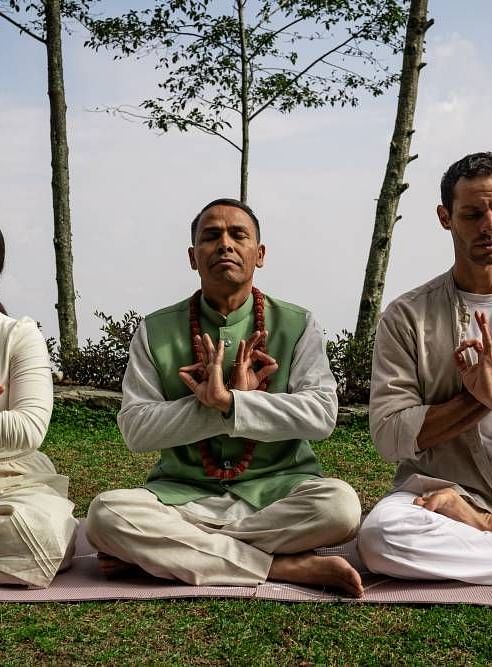 A front shot of three people sitting on the grass and meditating | Kavya Resort & Spa, Nagarkot