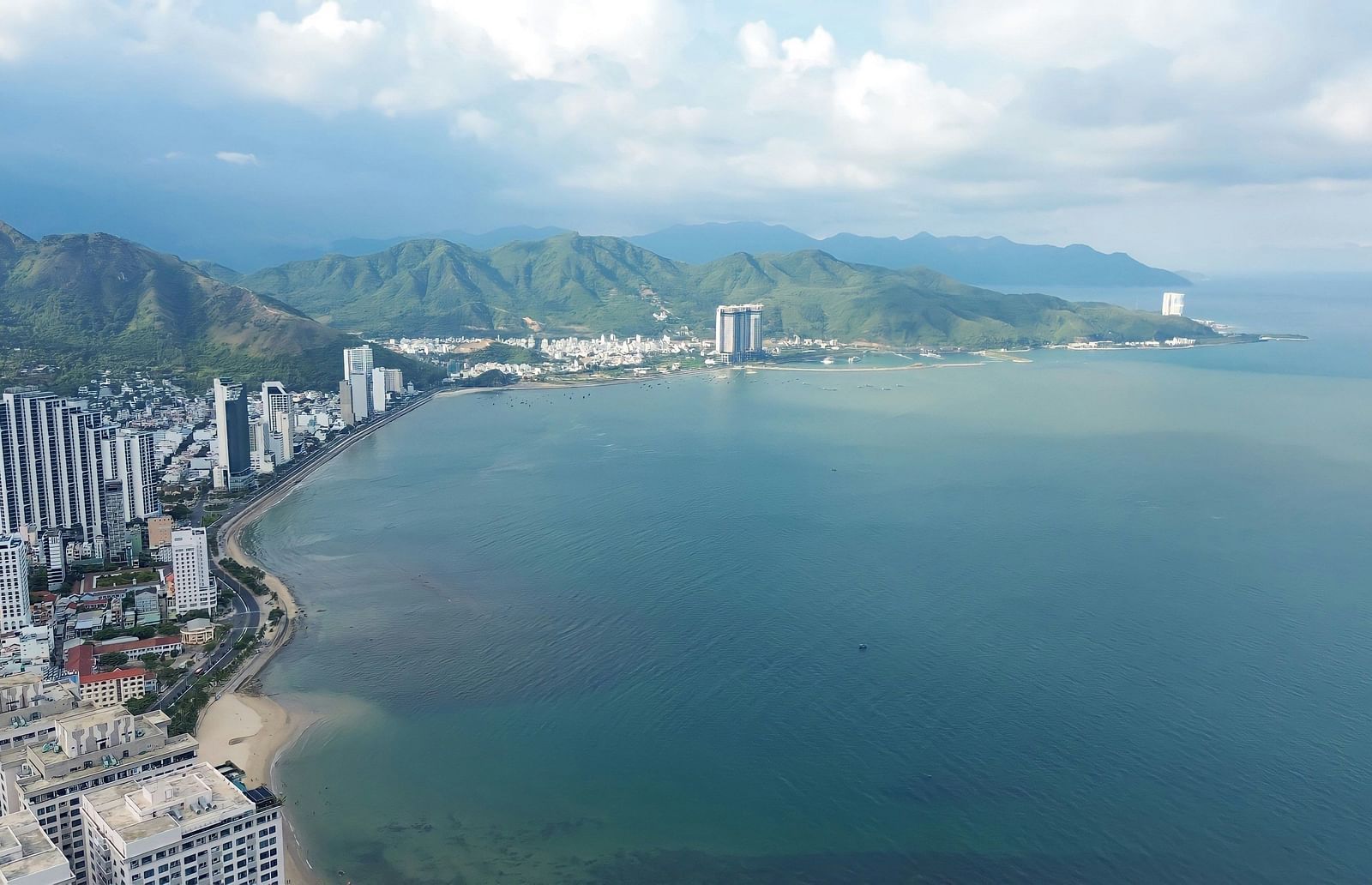 An overview of Bãi t?m Hòn Ch?ng with buildings, mountains and beach in view