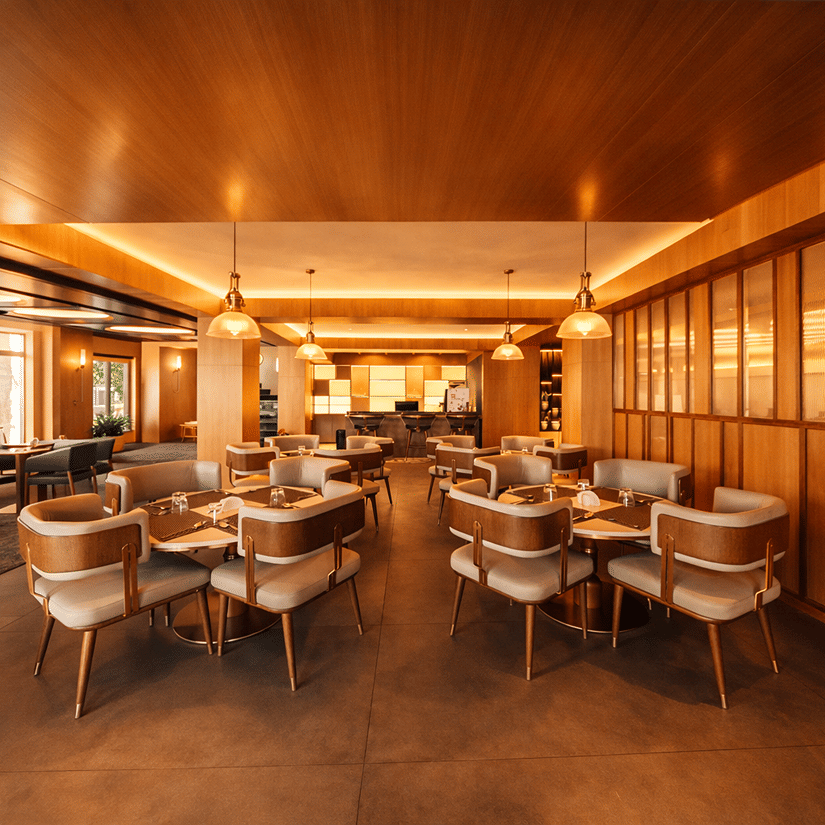A large restaurant space with multiple tables, chairs, and wooden panelled walls | Pride Premier Darjeeling