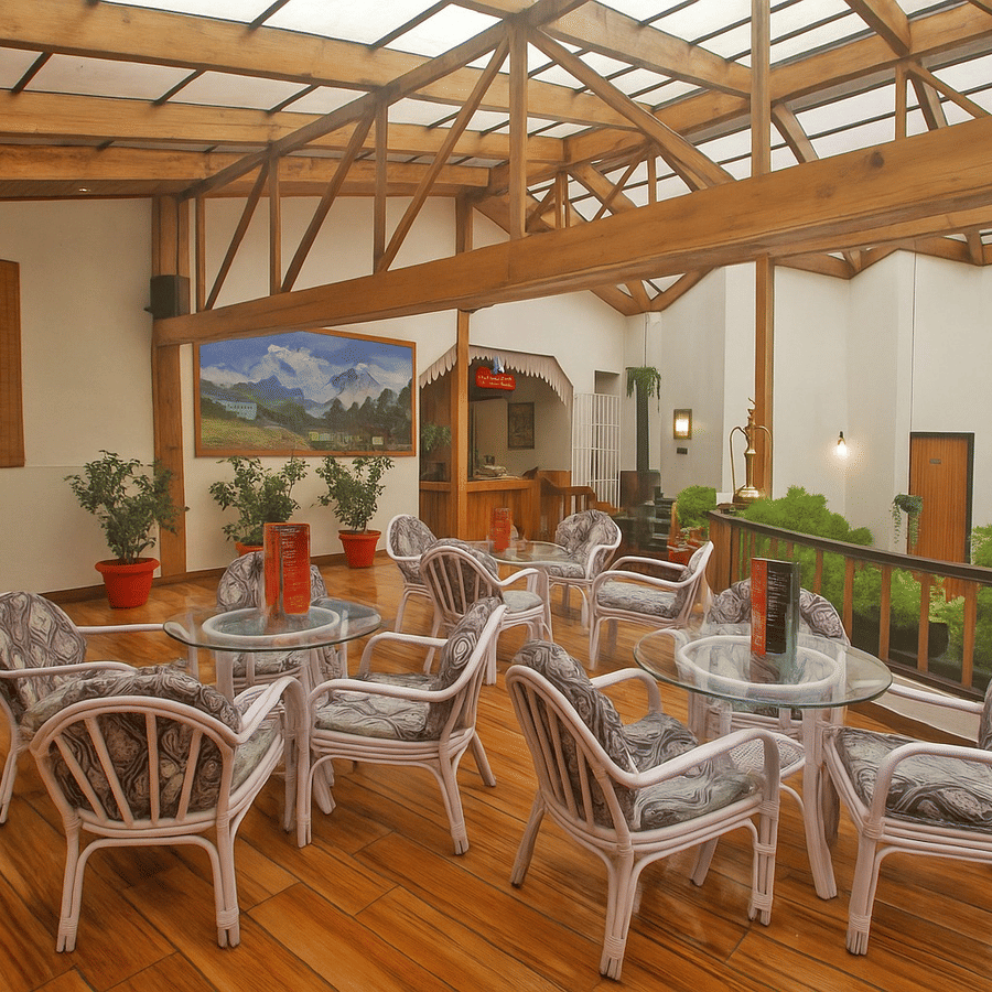 Well furnished Sunset Bar and Lounge at Central Heritage Resort and Spa, Darjeeling featuring several sets of table and chairs and a few flower pots at the corner