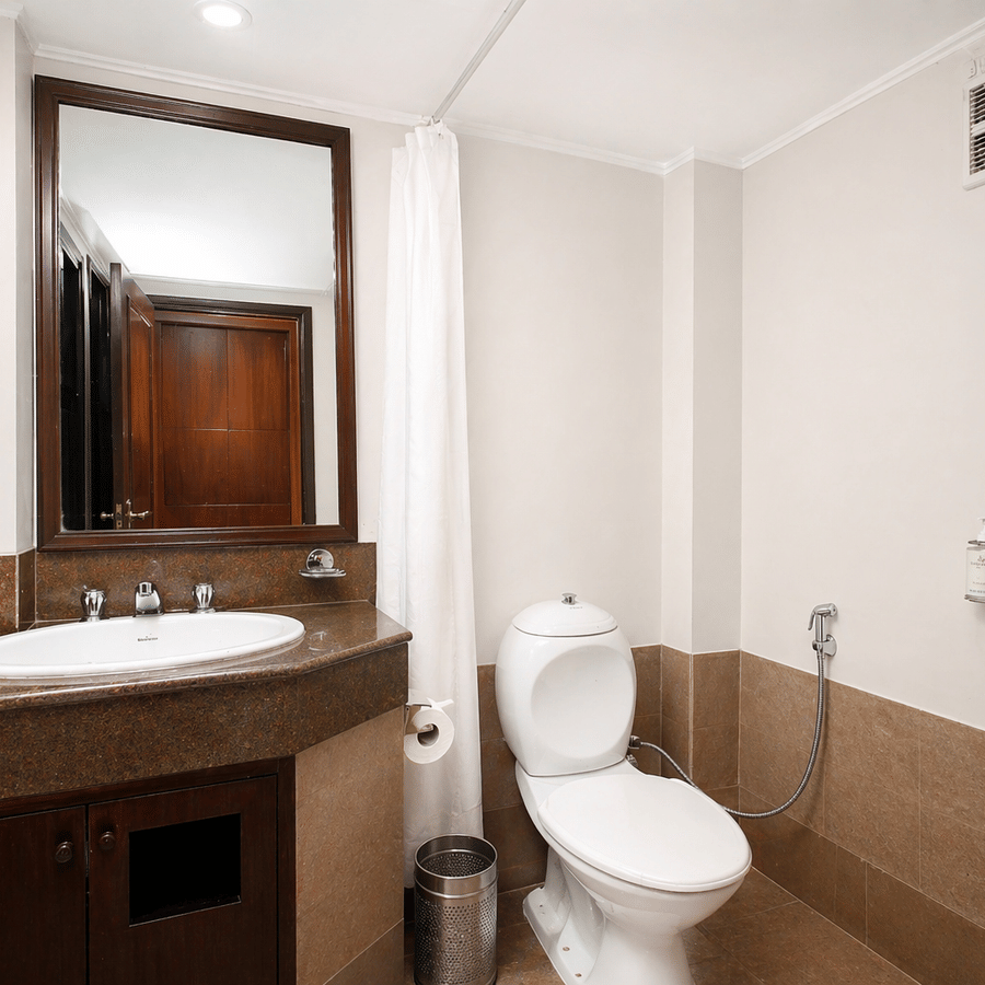 A bathroom at Central Hotels featuring a wall-mounted mirror vanity unit with sink toilet dark tiled flooring and white walls in a clean and compact layout.