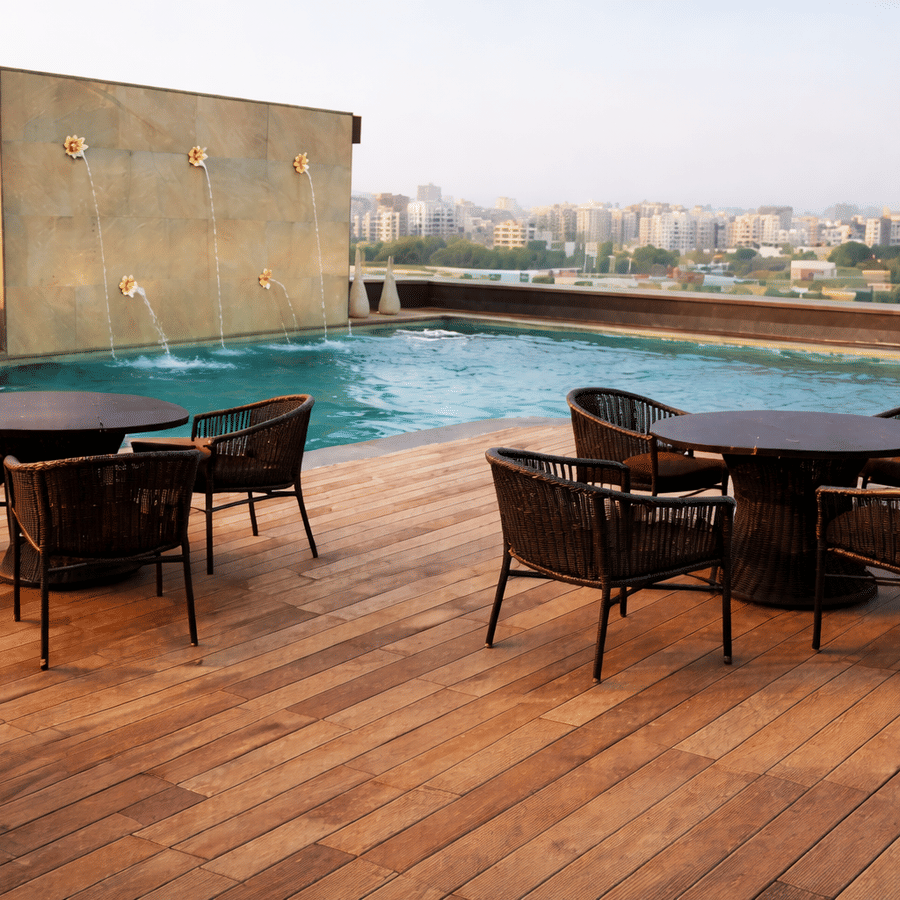 Rooftop pool deck during daytime featuring dark wicker dining sets on a wooden patio.