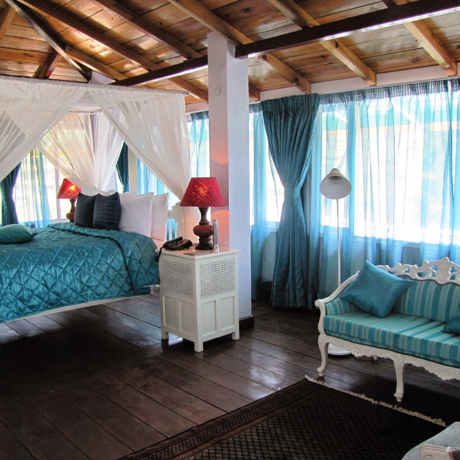 Room with bed and sitting area with sofa at Bed with side canopy and a lamp on the side of the bed at 3 bhk cottage at Te Aroha by Shervani Mukteshwar