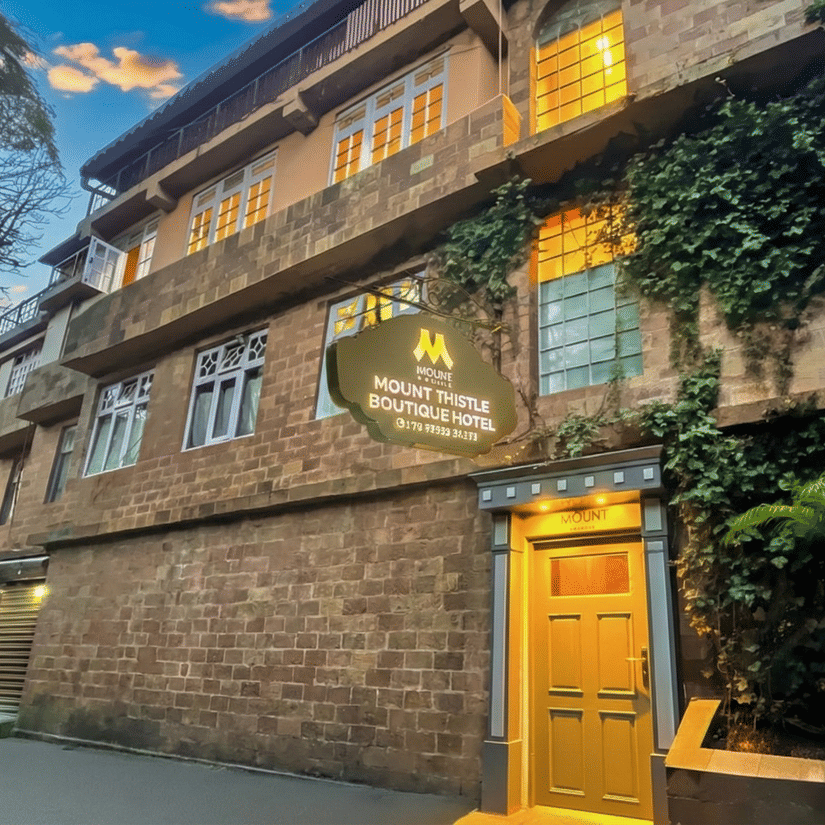 Mount Thistle Boutique Hotel in Darjeeling featuring a rustic stone exterior, ivy-covered walls, warm-lit windows, and a cosy boutique entrance.