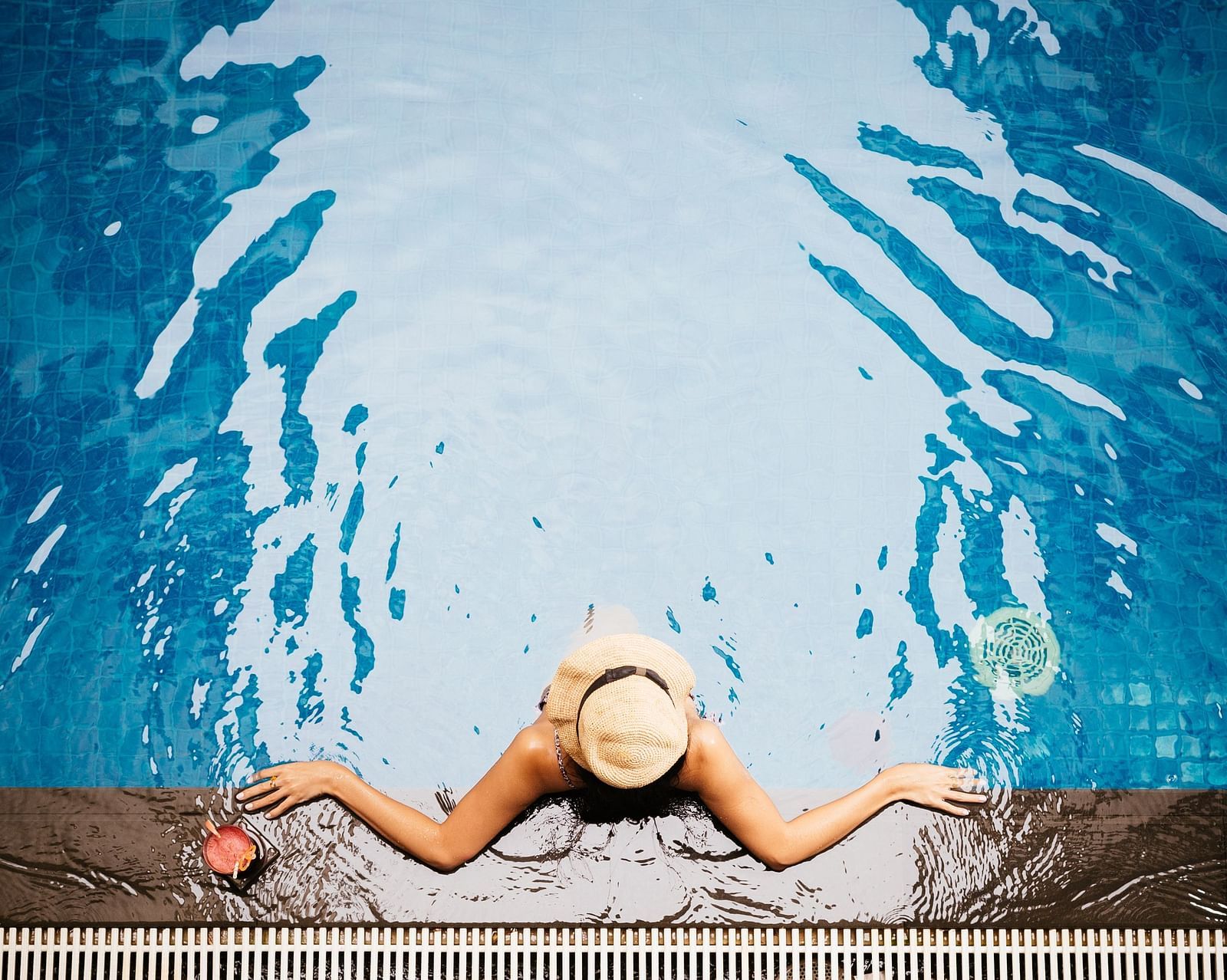 A woman is floating near the edge of the pool with a hat on her head | Central Mansions, Phnom Penh