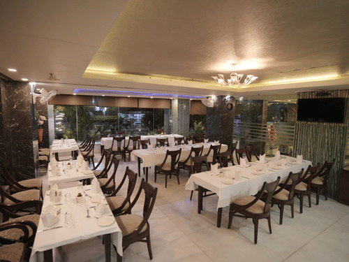 Indian Cuisine Restaurant - Dawat-e-Zaika featuring tables and chairs arranged under warm lighting at Hotel Atulyaa Taj, Agra