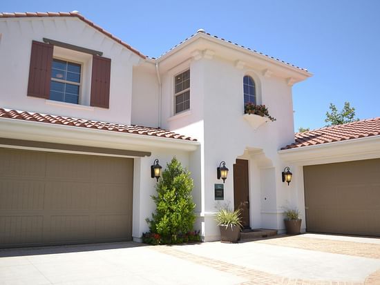 Overview shot of a villa with a entrance door and parking shutter with a backdrop of clear blue sky.