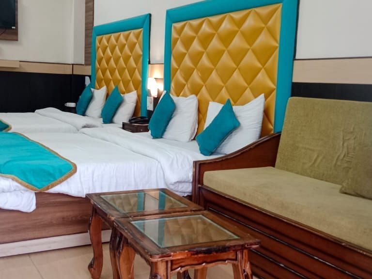 Four Bed Deluxe room with a sofa on the side at Hotel Panchvati Inn, Joshimath