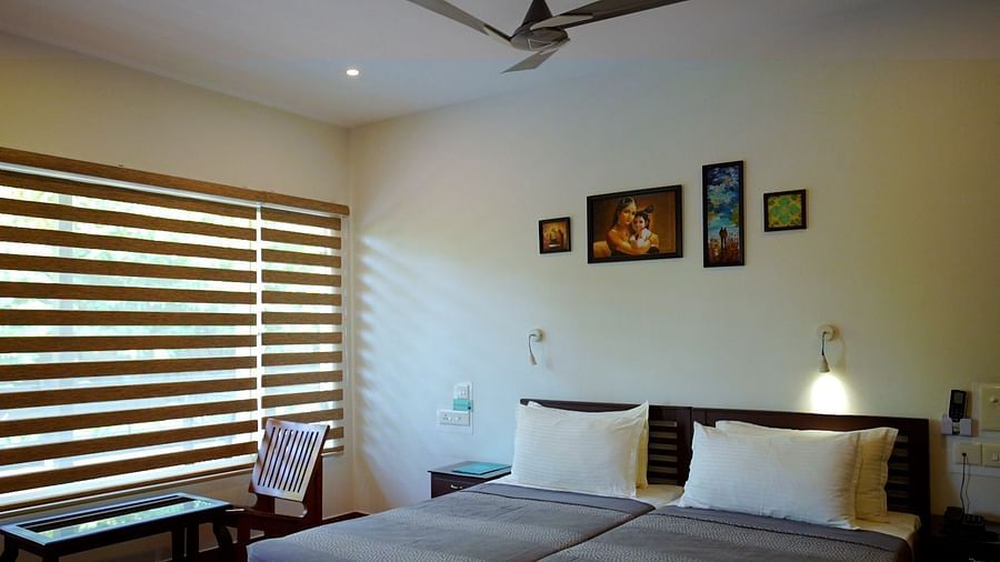 A simply furnished bedroom with a bed, desk, and window blinds.