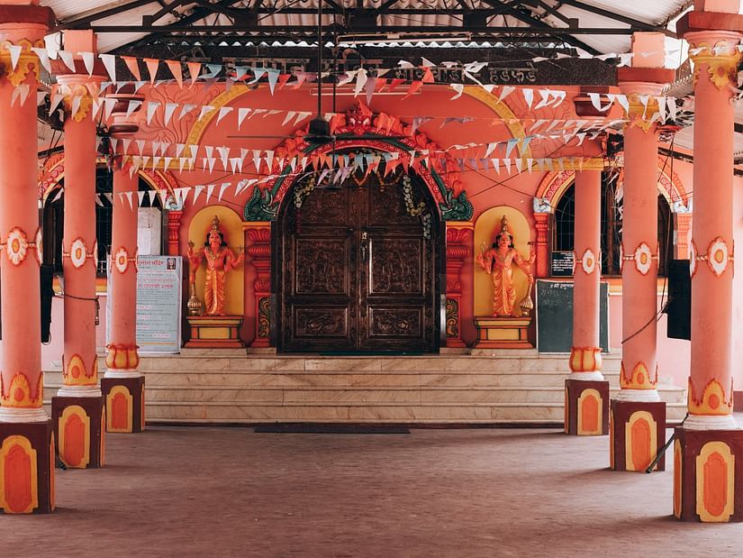 An ornately decorated temple entrance with colourful pillars and festive flags.