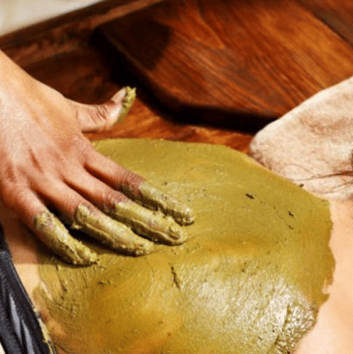 A practitioner applies a substance on the back of a person lying on a surface at YO1 Longevity & Health Resorts