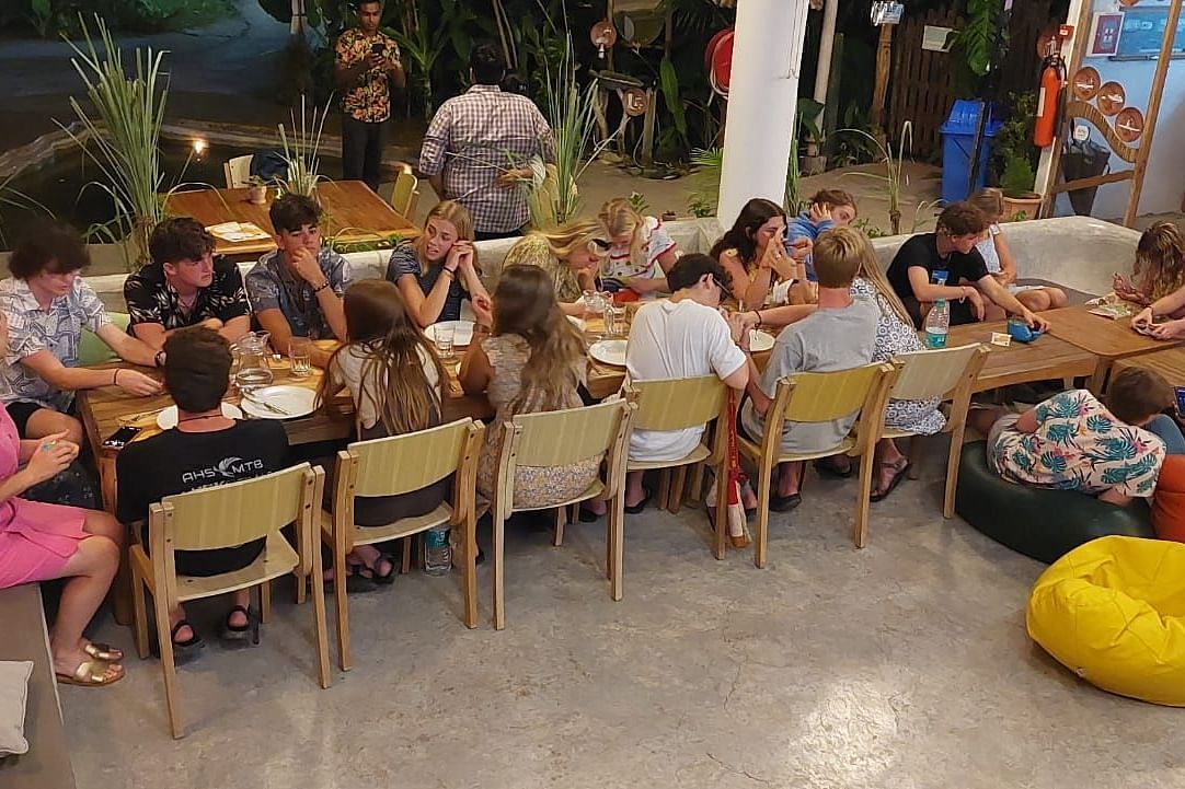 gathering of people sitting around a long dining table and seem engaged in laughter and conversation.