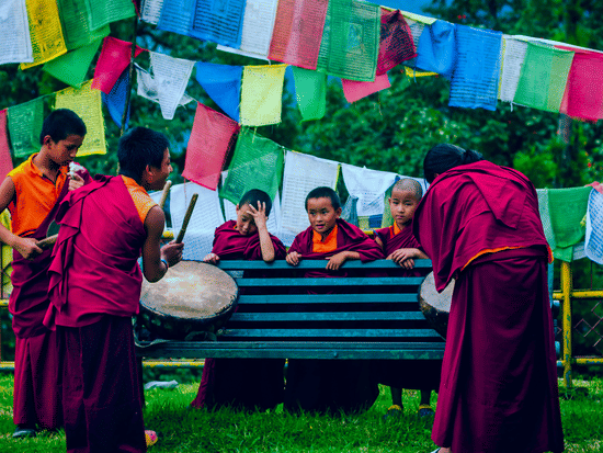 a group of monks playing drums in a park and having fun around a bench