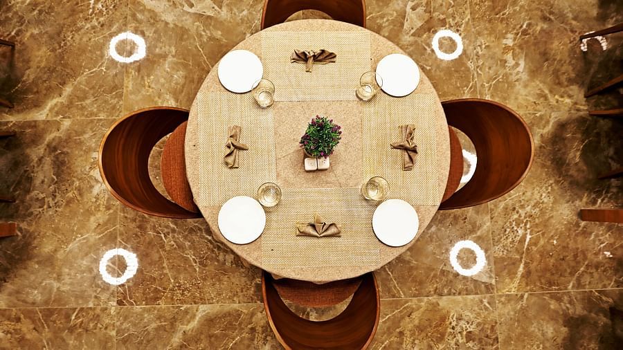A view of the table from above with four chairs tucked inside the table and cutlery on it - VITS Devbhumi, Dwarka