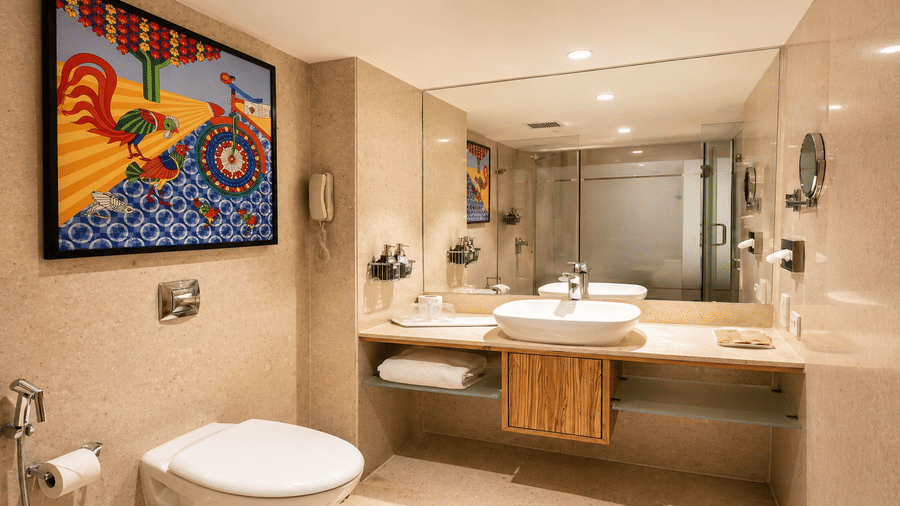 Warm-lit bathroom with marble counter, sink, mirror, and bathtub at Pride Plaza Ahmedabad.