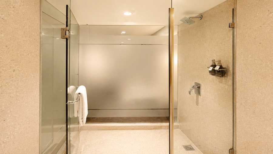Clean glass shower cubicle with wall fixtures and tiled floor at Pride Plaza Ahmedabad.
