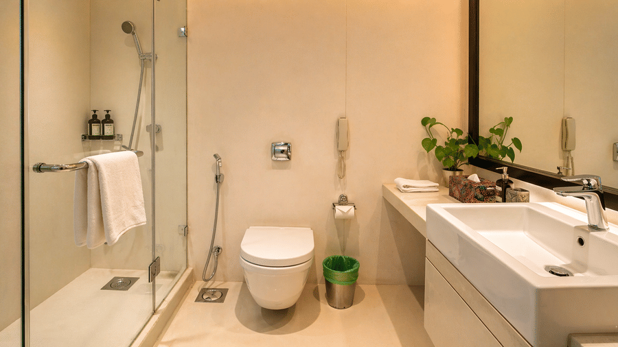 Modern bathroom at Pride Premier Pune with a vanity, toilet, walk in shower and wall mirror.