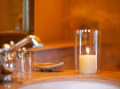 A close up shot pf a lit candle placed near the wash basin in the washroom - MANVAR Resort & Desert Camp