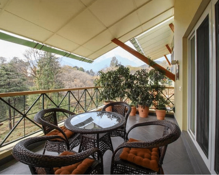 A private sit-out area in a balcony with a tea table and chairs outside a room facing the tea gardens and mountain - Lamrin Norwood Green, Palampur