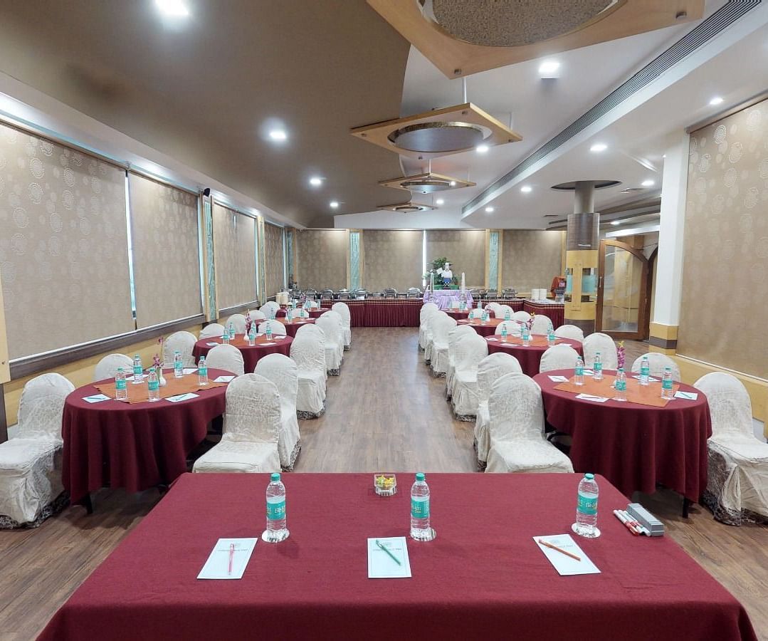 View from the stage of a well lit conference hall setup with designated tables and chairs