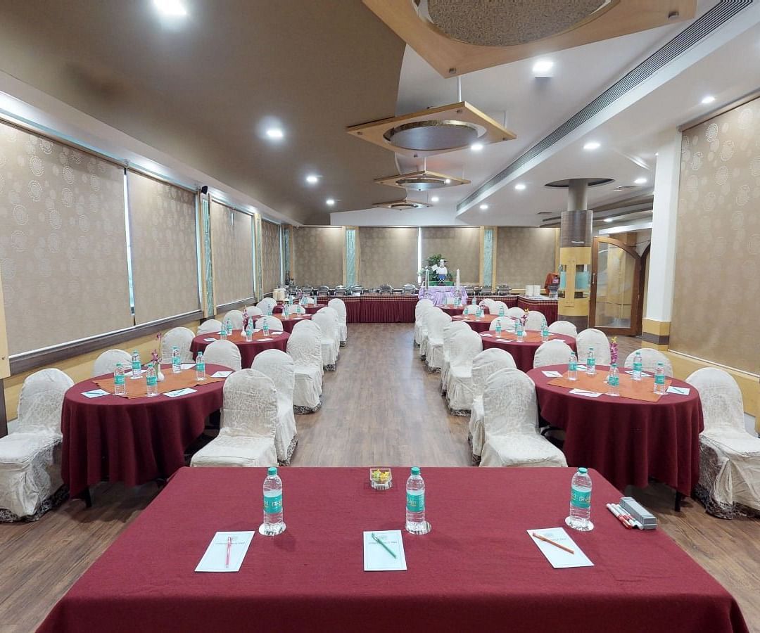 View from the stage of a well lit conference hall setup with designated tables and chairs