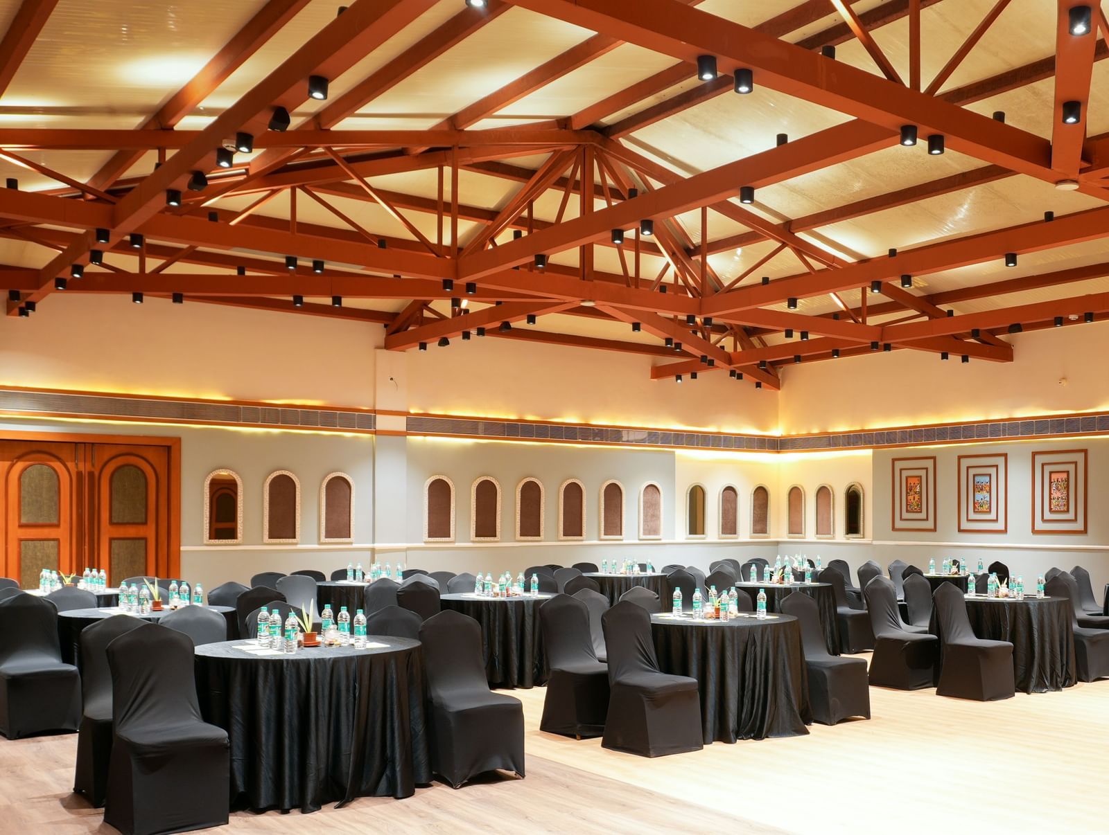 Om I in Vedic Village Spa Resort featuring tables and chairs wrapped in black furniture coverings and modern interiors.. 