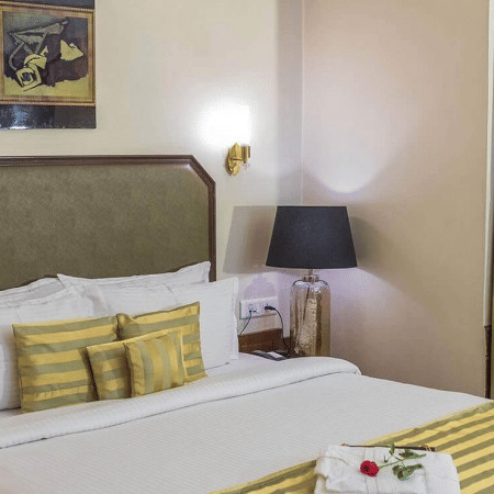 the view of a bed with yellow pillows and curtains covering the window - Polo Towers, Shillong